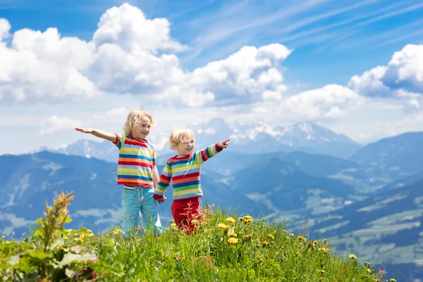 アルプスの山々で子供たちのハイキング 子供たちはオーストリアの雪に覆われた山を見てください 春休み 高山草原に咲くハイキングコースの小さな男の子 アウトドアの楽しさと健康的な活動 — ストック写真