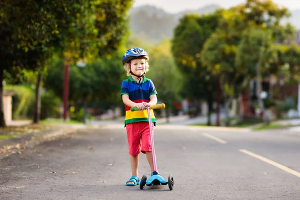 孩子们在公园里踢摩托车 孩子们学习滑板 在阳光明媚的夏日里滑冰的小男孩 儿童在安全居住街道上的户外活动 学龄前儿童的积极运动 — 图库照片