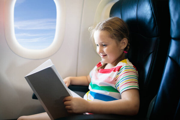 Child in airplane. Fly with family. Kids travel.