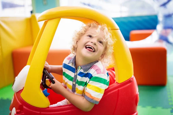 Criança montando carro de brinquedo. Menino com brinquedos . — Fotografia de Stock