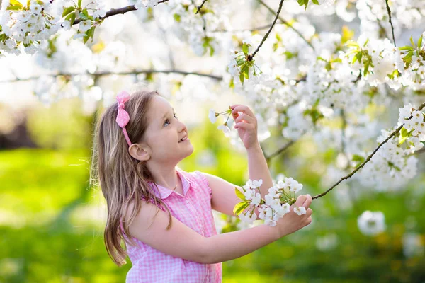 Kids play in spring park. Little girl with flowers — Stock Photo, Image