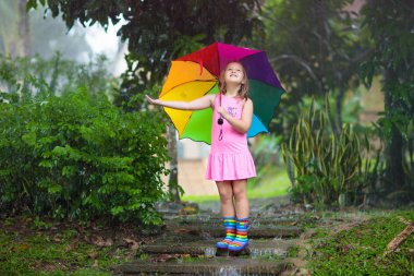 Kid with umbrella playing in summer rain. clipart