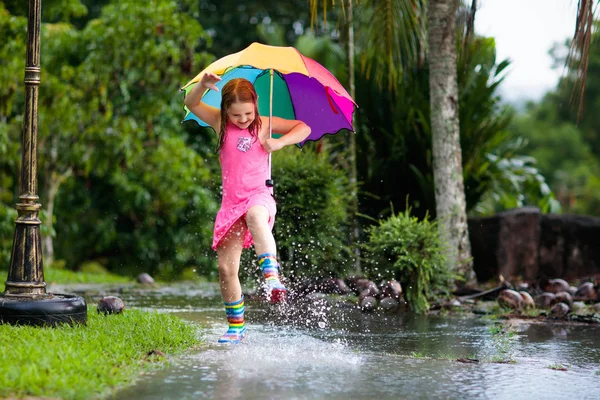 Мальчик с зонтиком играет в летний дождь . — стоковое фото