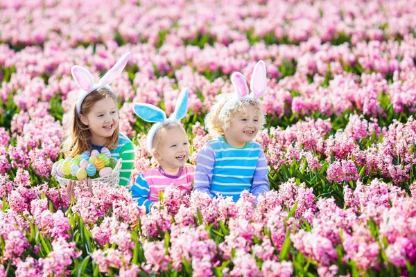 Kinderen op eieren zoeken met Pasen in de bloeiende tuin. — Stockfoto