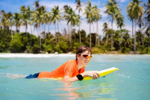 Bambino che fa surf sulla spiaggia tropicale. Surfista in oceano . — Foto Stock