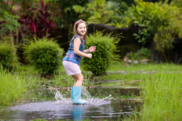 Kid with umbrella playing in summer rain. — Stock Photo, Image