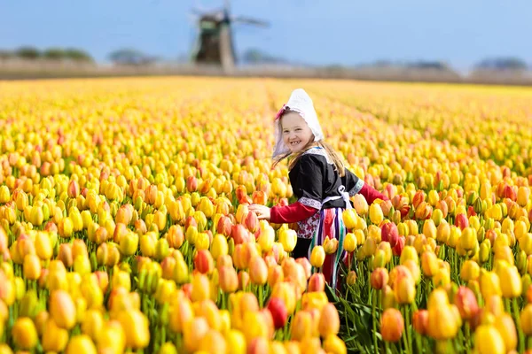 Kind in tulp bloem veld. Windmolen in Nederland. — Stockfoto