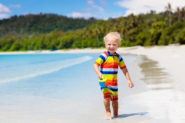 Dzieci grają na tropikalnej plaży. Zabawki do piasku i wody. — Zdjęcie stockowe
