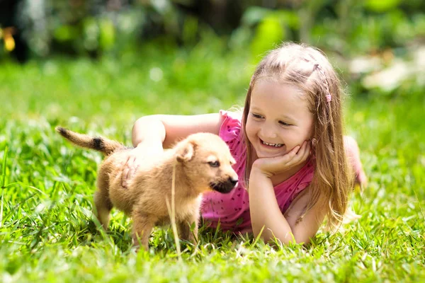 Les enfants jouent avec le chiot. Enfants et chien dans le jardin . — Photo