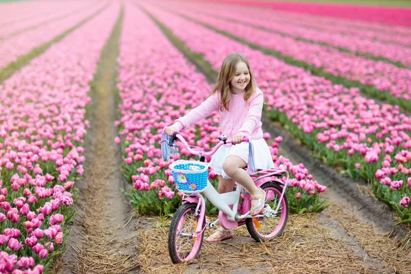 Kind auf Fahrrad im Tulpenfeld. Fahrrad in Holland. — Stockfoto