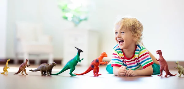 Niño jugando con dinosaurios de juguete. Juguetes infantiles . — Foto de Stock