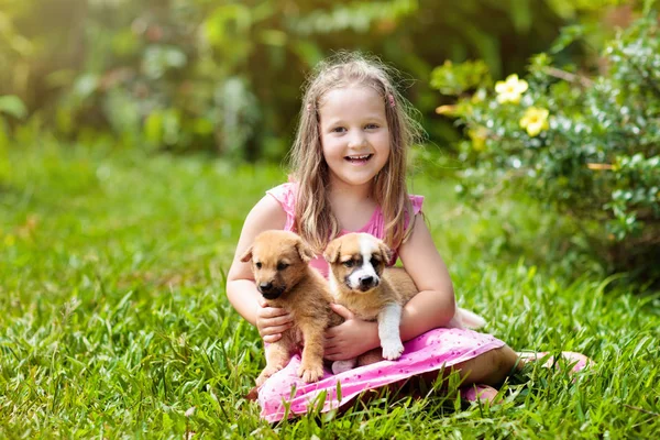 Les enfants jouent avec le chiot. Enfants et chien dans le jardin . — Photo