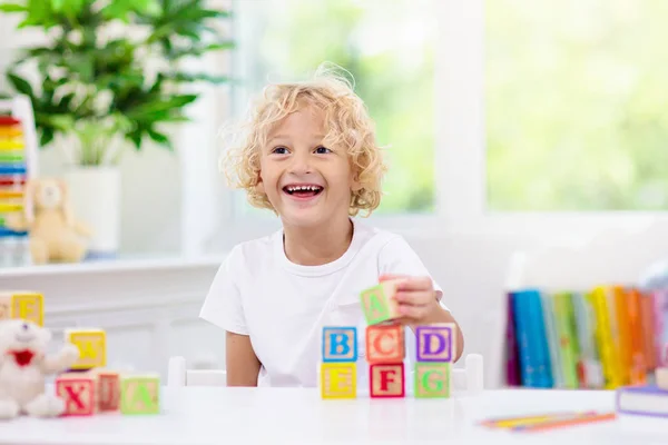 Onderliggende leer brieven. Kid met houten ABC blokken — Stockfoto