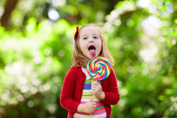 Μικρό κορίτσι με γλειφιτζούρι πολύχρωμα καραμέλα — Φωτογραφία Αρχείου