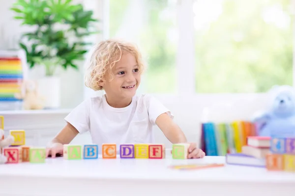 Letras de aprendizaje infantil. Niño con bloques de madera abc —  Fotos de Stock