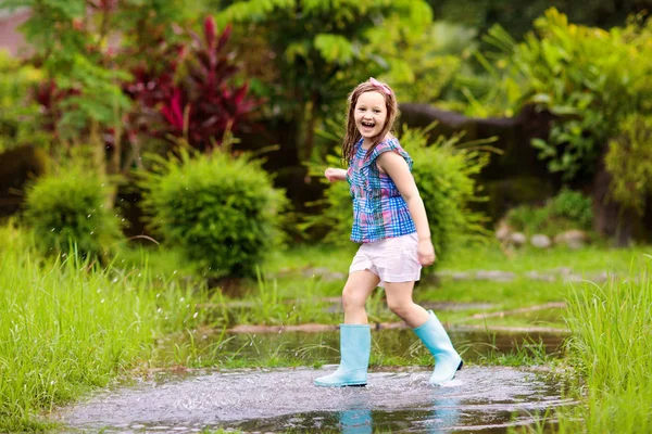 Niño con paraguas jugando bajo la lluvia de verano . — Foto de Stock