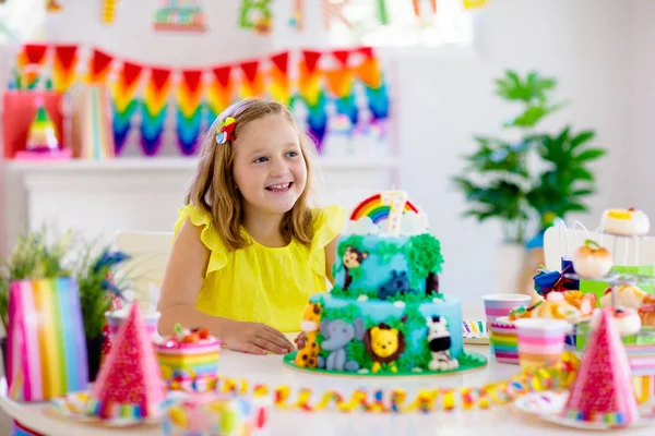 Fiesta de cumpleaños infantil. Los niños soplan vela en la torta . — Foto de Stock