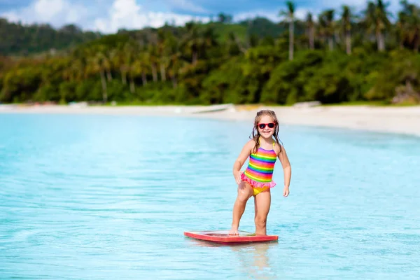 Kids surf on tropical beach. Vacation with child. Stock Picture