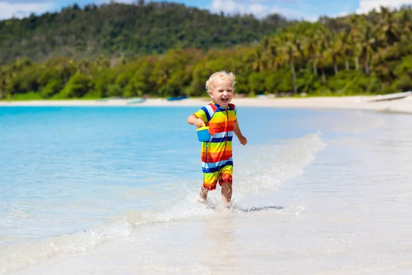 Dzieci grają na tropikalnej plaży. Zabawki do piasku i wody. — Zdjęcie stockowe