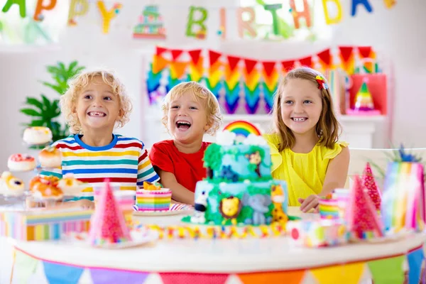 Fiesta de cumpleaños infantil. Los niños soplan vela en la torta . — Foto de Stock