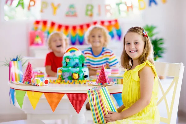 Fiesta de cumpleaños infantil. Los niños soplan vela en la torta . — Foto de Stock
