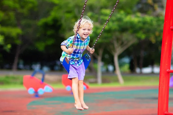 Criança no parque infantil. swing Kids jogar ao ar livre . — Fotografia de Stock