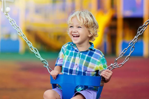 Bambino al parco giochi. swing bambini giocare all'aperto . — Foto Stock