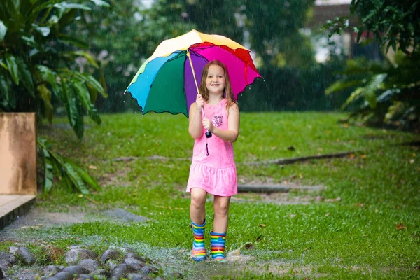 Dziecko z parasolem, grając w letni deszcz. — Zdjęcie stockowe