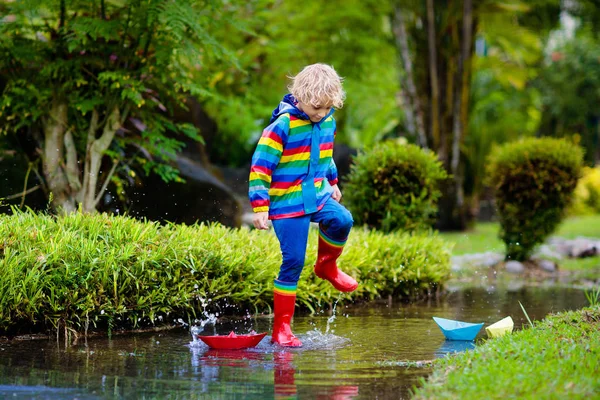 Child with paper boat in puddle. Kids by rain. — Stock Photo, Image