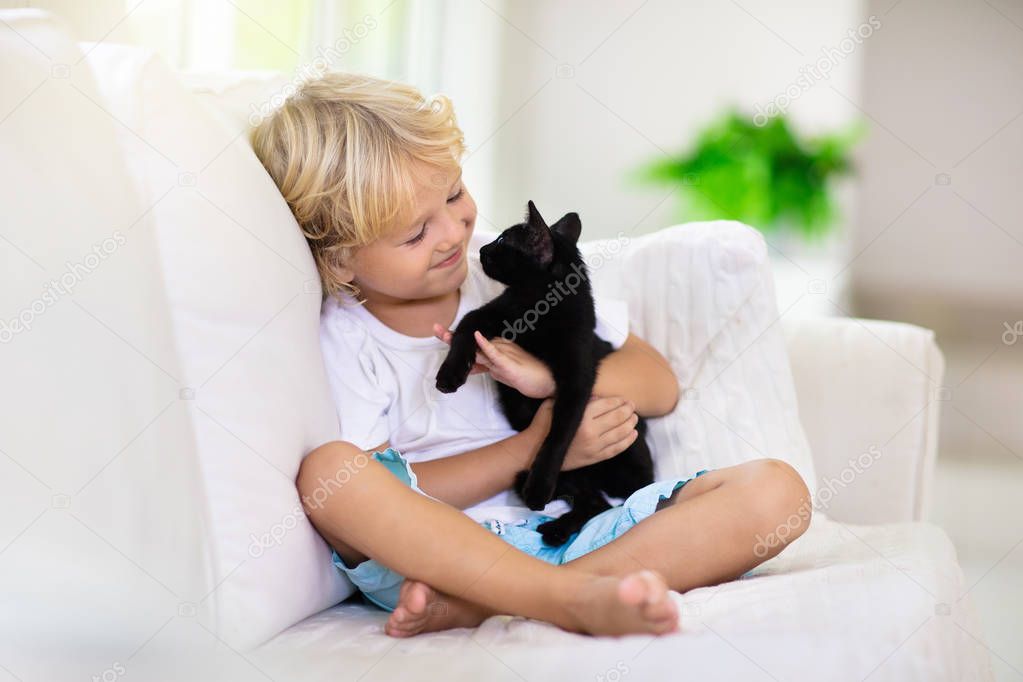 Child playing with baby cat. Kid and kitten.