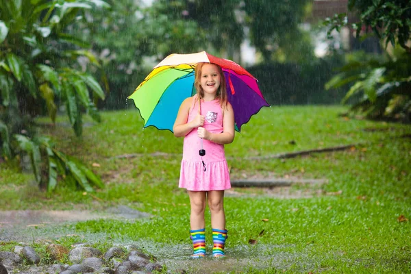 Niño con paraguas jugando bajo la lluvia de verano . — Foto de Stock