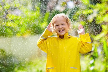 Yağmurda oynayan çocuk. Şemsiyeli çocuk.