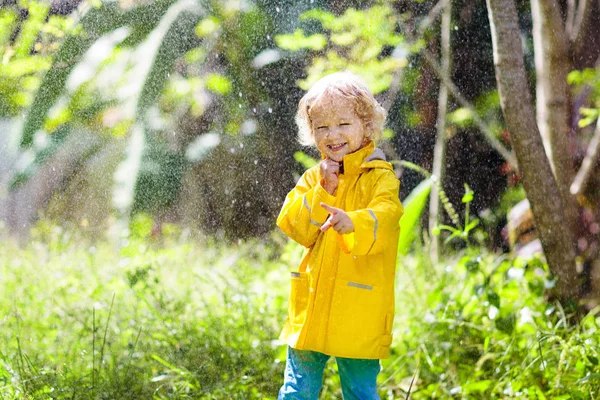 Un niño jugando bajo la lluvia. Niño con paraguas . — Foto de Stock