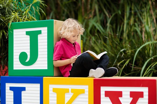 Child reading book. Kid learning letters.