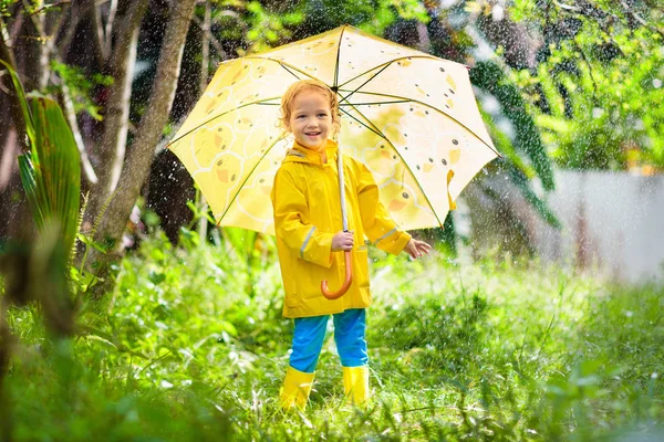 Copilul se joacă în ploaie. Copil cu umbrelă . — Fotografie, imagine de stoc