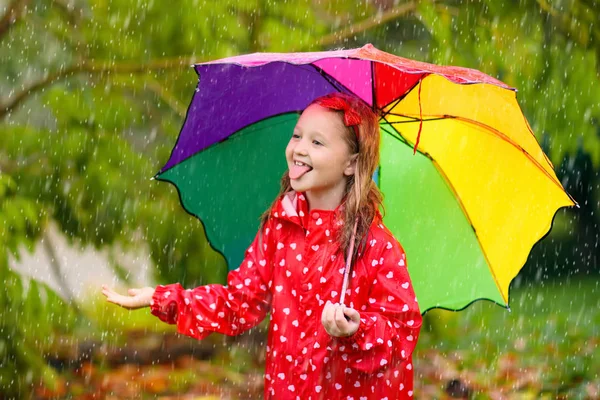 Kind mit Regenschirm spielt im Sommerregen. — Stockfoto