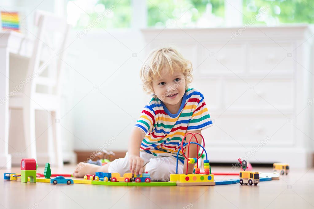 Kids play wooden railway. Child with toy train.