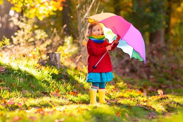 Kind mit Regenschirm spielt im Herbstregen. — Stockfoto