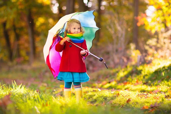 Ребенок с зонтиком играет в осенний дождь . — стоковое фото