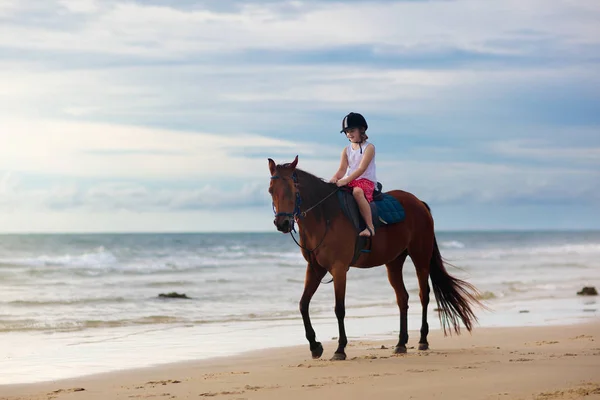 Enfants chevauchant à cheval sur la plage. Les enfants montent à cheval . — Photo