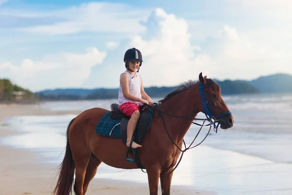 Barn ridning häst på stranden. Barn rida hästar. — Stockfoto