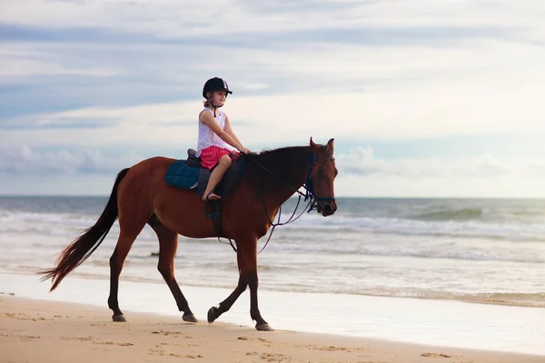 Enfants chevauchant à cheval sur la plage. Les enfants montent à cheval . — Photo