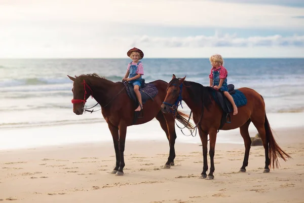 Enfants chevauchant à cheval sur la plage. Les enfants montent à cheval . — Photo