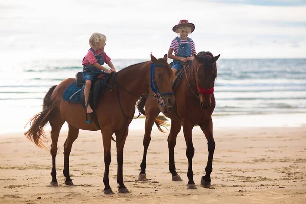 Enfants chevauchant à cheval sur la plage. Les enfants montent à cheval . — Photo