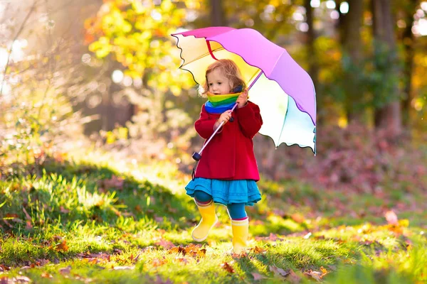 Niño con paraguas jugando bajo la lluvia de otoño . — Foto de Stock