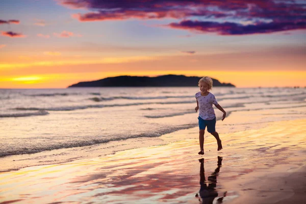 Child playing on ocean beach. Kid at sunset sea. — Stock Photo, Image