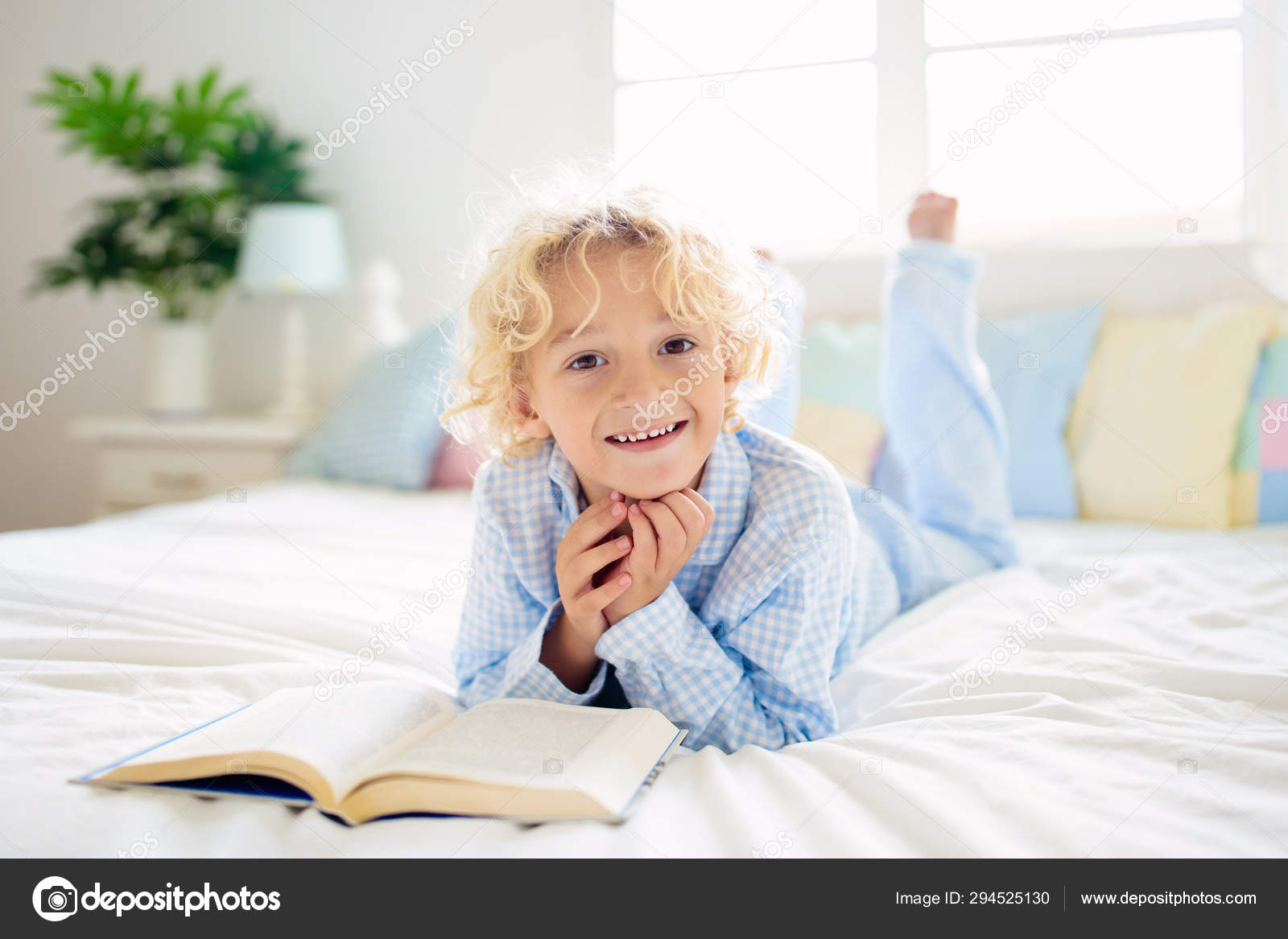 Child reading book in bed. Kids read in bedroom. Stock Photo by