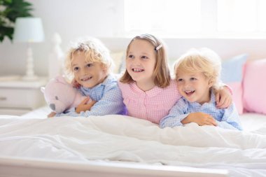 Çocuklar yatakta oynar. Evde çocuklar.