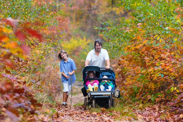 Family hiking with stroller in autumn park — Stock Photo, Image