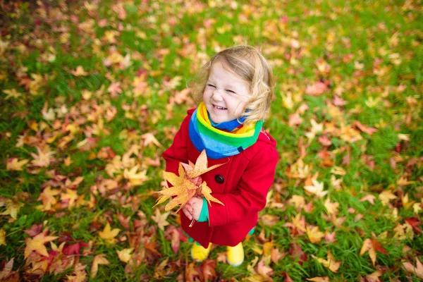 Kleines Mädchen spielt im Herbst mit Ahornblatt — Stockfoto